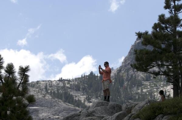 FILE - In this Aug. 8, 2017 file photo, a man gets a scenic view of Emerald Bay near South Lake Tahoe, Calif. The postcard photos of Emerald Bay are as iconic as those of another famous California landmark, the Golden Gate Bridge. As winds picked up Monday, Aug. 30, 2021, the Caldor Fire roared over the Sierra crest and bore down on the southern end of Lake Tahoe. (AP Photo/Rich Pedroncelli, File)