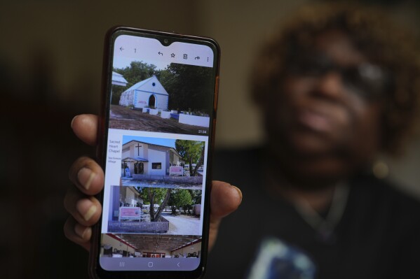 Chagossian Bernadette Dugasse shows photos of a church in the Chagos Islands during an interview with The Associated Press, at her home in London, Tuesday, March 25, 2025. (AP Photo/Kin Cheung)
