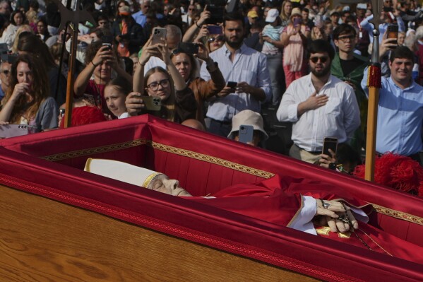 The body of Pope Francis is carried into St. Peter's Basilica at the Vatican, Wednesday, April 23, 2025, where he will lie in state for three days. (AP Photo/Emilio Morenatti)