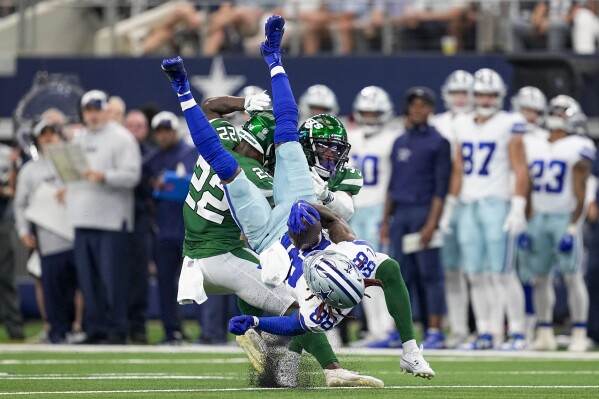 Dallas Cowboys wide receiver CeeDee Lamb is tackled by New York Jets safety Tony Adams and cornerback Michael Carter II. during the first half of an NFL football game in Arlington, Texas, Sunday, Aug. 17, 2023. (AP Photo/Tony Gutierrez)
