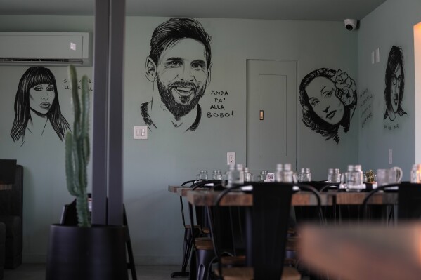 Art depicting Argentine soccer player Lionel Messi adorns the wall at Kao Bar & Grill in Hallandale Beach, Fla., Monday, July 10, 2023. Alongside the image of Messi is written the Spanish phrase "¡Anda pa' alla bobo!", which roughly translates to "Go away, fool," part of a Messi outburst during the Qatar 2022 World Cup which became an internet meme. (AP Photo/Rebecca Blackwell)