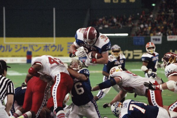 
              FILE - In this Jan. 12, 1992 file photo, East's Kevin Turner, of Alabama, dives over the top for a touchdown in the fourth quarter of the Japan Bowl, the American collegiate all-star football game, at the Tokyo Dome. A fullback at Alabama before playing eight years in the NFL for New England and Philadelphia, Kevin Turner was 46 when he died in 2016. He had been diagnosed with amyotrophic lateral sclerosis, known as ALS or Lou Gehrig's disease, but after studying his brain researchers declared that it was actually CTE. (AP Photo/Itsuo Inouye, File)
            