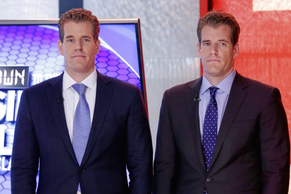 Cameron Winklevoss, left, and Tyler Winklevoss, founders of Gemini Trust Co., wait to appear on the "Countdown to the Closing Bell with Liz Claman" program, on the Fox Business Network, in New York, Oct. 8, 2015. (AP Photo/Richard Drew, File)