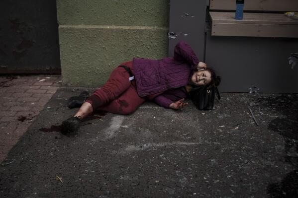 An injured woman lies on the sidewalk during a Russian bombardment in Kharkiv, Ukraine, Sunday, April 17, 2022. (AP Photo/Felipe Dana)