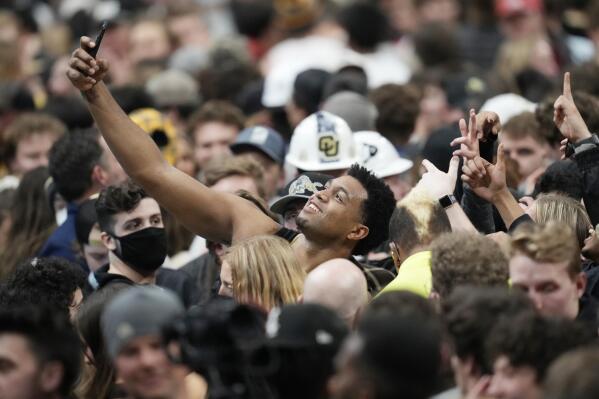 Colorado forward Evan Battey, center, takes a photo with fans after they rushed the floor after an NCAA college basketball game against Arizona, Saturday, Feb. 26, 2022, in Boulder, Colo. (AP Photo/David Zalubowski)