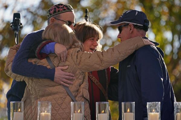 People hug after lighting a candle in memory of Melvin Wax, one of 11 worshippers killed four years ago when a gunman opened fire at the Tree of Life synagogue in the Squirrel Hill neighborhood, during a commemoration ceremony in Pittsburgh on Thursday, Oct. 27, 2022. (AP Photo/Gene J. Puskar)