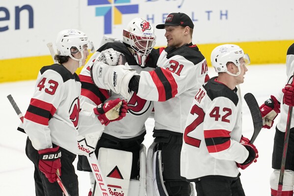 New Jersey Devils goaltender Jake Allen, center left, is congratulated by Luke Hughes (43), Kaapo Kahkonen (31) and Curtis Lazar (42) after the team's win in an NHL hockey game against the Dallas Stars in Dallas, Thursday, March 14, 2024. (AP Photo/Tony Gutierrez)