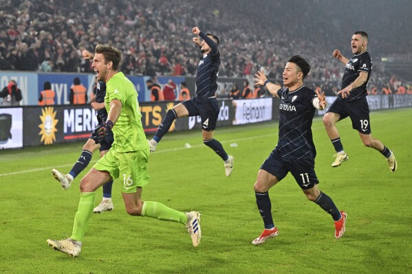 Bochum goalkeeper Andreas Luthe, front left, celebrates with teammates after winning a penalty shootout in a Bundesliga soccer match against Fortuna Duesseldorf in Duesseldorf, Germany, Monday, May 27, 2024. (Marius Becker/dpa via AP)