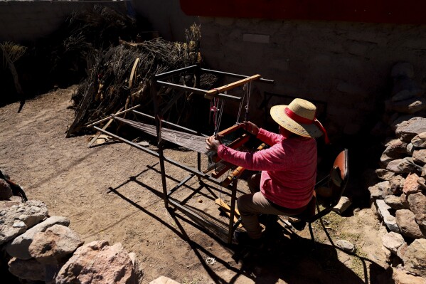 Teófila Challapa teje en su telar en su casa de Cariquima, Chile, el lunes 31 de julio de 2023. Challapa, de 59 años, aprendió a telar desde pequeña. “Aprendí de muy niña, cuando iba pastoreando los animales y me fui criando con los mismos hábitos de mis abuelitos”.reza antes de trabajar", dijo. (AP Foto/Ignacio Muñoz)