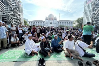 Members of the Pan-Malaysian Islamic Party wait outside the Palace of Justice, background, as they await the Federal Court's decision on Kelantan state's sharia law criminal enactment, in Putrajaya, Malaysia Friday, Feb. 9, 2024. Malaysia's top court Friday struck down over a dozen Shariah-based state laws, saying they encroached on federal authority, a decision denounced by Islamists who fear it could undermine religious courts across the country.(AP Photo)