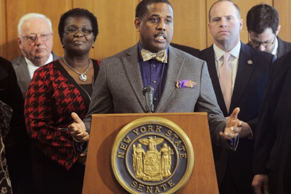 FILE - New York Sen. Kevin Parker, D-Brooklyn, stands at the podium, flanked by Senate members, Feb. 6, 2017, during a news conference at the Capitol in Albany, N.Y. A disability rights advocate made a complaint to New York State Police saying he was shoved twice in the state Capitol building by Parker, a Brooklyn Democrat with a history of violent behavior. (AP Photo/Hans Pennink, File)