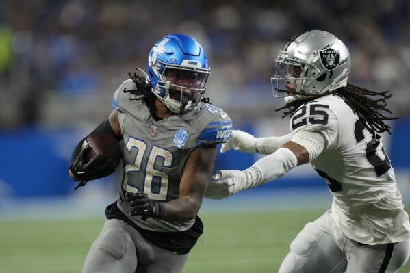 Detroit Lions running back Jahmyr Gibbs (26) rushes against the defense of Las Vegas Raiders safety Tre'von Moehrig (25) during the second half of an NFL football game, Monday, Oct. 30, 2023, in Detroit. (AP Photo/Paul Sancya)