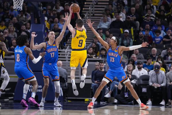 Indiana Pacers guard T.J. McConnell (9) shoots between Oklahoma City Thunder forward Aleksej Pokusevski (17) and forward Ousmane Dieng (13) during the first half of an NBA basketball game in Indianapolis, Friday, March 31, 2023. (AP Photo/Michael Conroy)