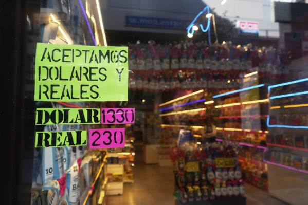 A sign displays the exchange rate between the U.S. dollar and the Argentine peso that is used at the store in Buenos Aires, Argentina, Monday, April 14, 2025. (AP Photo/Natacha Pisarenko)