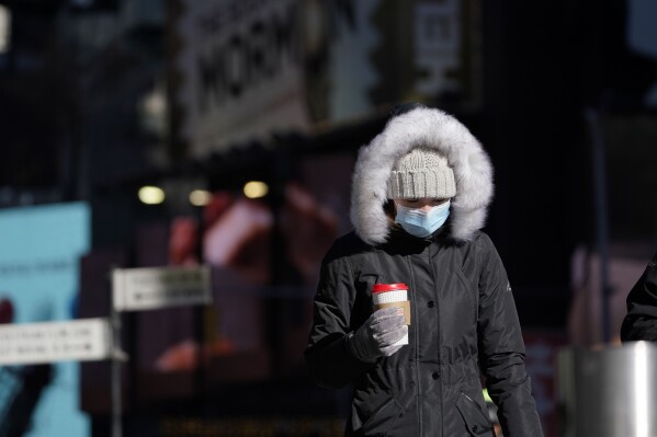 FILE - A pedestrian wears a heavy coat against the cold in New York, Tuesday, Jan. 11, 2022. January can be the worst month for respiratory illnesses and vaccination rates are low. When relatives, friends and co-workers are coming down with coughs, nasal congestion, fatigue and fever, keeping viruses at bay means thorough hand-washing, good ventilation and wearing a mask in crowded areas. (AP Photo/Seth Wenig, File)