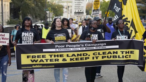 FILE - Jackson residents and supporters hold signs as they march to the Governor's Mansion in Jackson, Miss., to protest the ongoing water issues, poverty and other social ills, in the city, Oct. 10, 2022. A federal judge on Thursday, June 29, 2023, temporarily blocked a new Mississippi law that requires people to get permission from state police before having protests or other gatherings near state government buildings in Jackson. (AP Photo/Rogelio V. Solis, File)