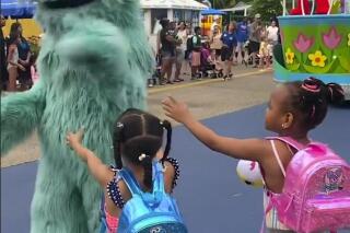 In this image from video provided by Jodi Brown, posted to Instagram on Saturday, July 16, 2022, a performer dressed as the character Rosita waves off Brown's daughter and another 6-year-old Black girl at the Sesame Place amusement park in Langhorne, Pa. (Jodi Brown via AP)