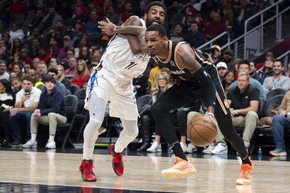 Atlanta Hawks guard Dejounte Murray, right, drives to the basket pass Brooklyn Nets guard Kyrie Irving during the first half of an NBA basketball game, Wednesday, Dec. 28, 2022, in Atlanta. (AP Photo/Hakim Wright Sr.)