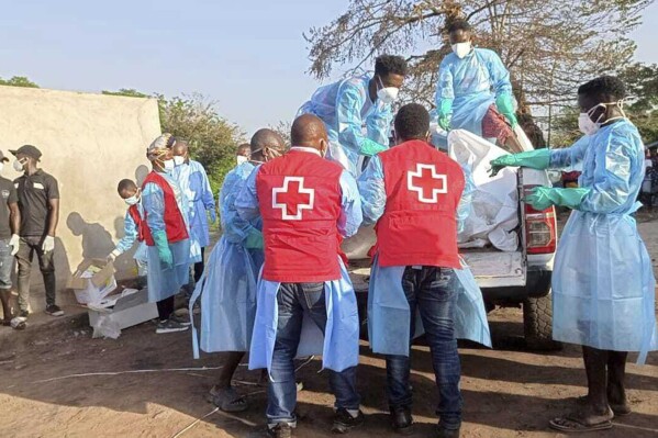 In this photo provided by the Liberia National Red Cross Society, health workers from the Liberia National Red Cross Society and the Bong County Health Team move the bodies of victims of a tanker explosion in Totota, Liberia, Tuesday Dec. 26, 2023. Authorities in Liberia say a leaking fuel tanker exploded as people gathered to collect the gasoline, leaving more than 40 dead. Officials say the blast on Tuesday also injured at least 83 people in Totota town in the central part of the West African country. (Liberia National Red Cross Society via AP)