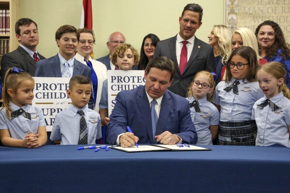 FILE - Florida Gov. Ron DeSantis signs the Parental Rights in Education bill, also known as the "Don't Say Gay" bill, at Classical Preparatory School, March 28, 2022, in Shady Hills, Fla. Students and teachers will be able to speak freely about sexual orientation and gender identity in Florida classrooms, provided it’s not part of instruction, under a settlement reached Monday, March 11, 2024, between Florida education officials and civil rights attorneys who had challenged a state law which critics dubbed “Don't Say Gay.” (Douglas R. Clifford/Tampa Bay Times via AP, File)