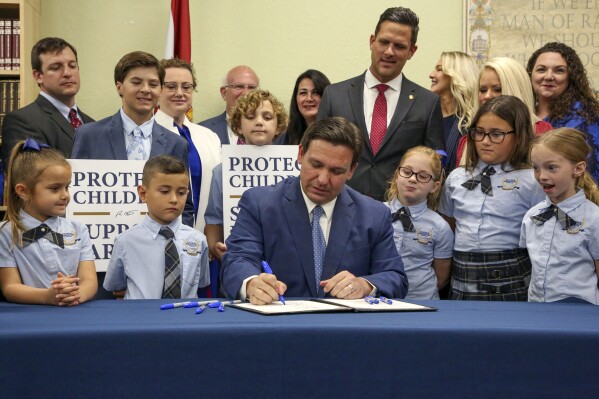 FILE - Florida Gov. Ron DeSantis signs the Parental Rights in Education bill, also known as the "Don't Say Gay" bill, at Classical Preparatory School, March 28, 2022, in Shady Hills, Fla. Students and teachers will be able to speak freely about sexual orientation and gender identity in Florida classrooms, provided it’s not part of instruction, under a settlement reached Monday, March 11, 2024, between Florida education officials and civil rights attorneys who had challenged a state law which critics dubbed “Don't Say Gay.” (Douglas R. Clifford/Tampa Bay Times via AP, File)