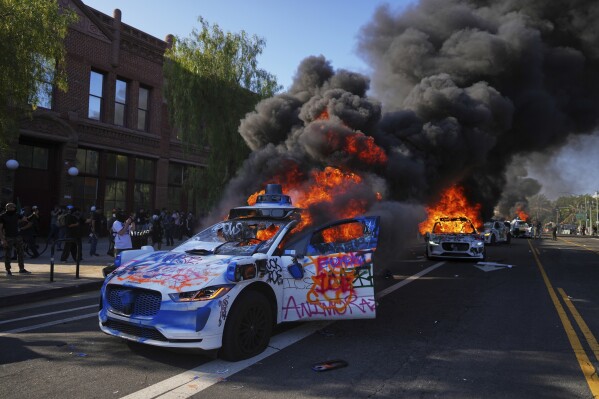Multiple Waymo taxis burn near the Metropolitan Detention Center of downtown Los Angeles, Sunday, June 8, 2025, following last night's immigration raid protest. (AP Photo/Eric Thayer)