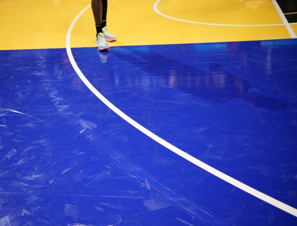 A faint arc, left, where the 3-point line was incorrectly painted on the floor, can still be seen outside the actual 3-point line, during the second half of an NBA basketball in-season tournament game between the Dallas Mavericks and Denver Nuggets on Friday, Nov. 3, 2023, in Denver. (AP Photo/David Zalubowski)