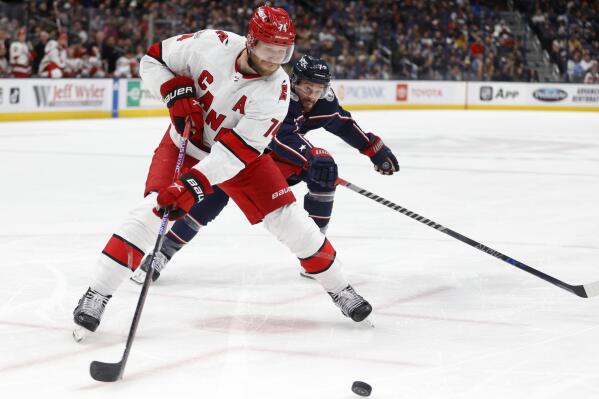 Carolina Hurricanes defenseman Jaccob Slavin, left, reaches for the puck in front of Columbus Blue Jackets forward Sean Kuraly during the second period of an NHL hockey game in Columbus, Ohio, Thursday, Jan. 12, 2023. (AP Photo/Paul Vernon)