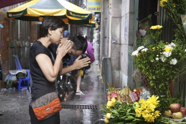People pray in front of a make shift shrine set up in front of a building that was caught on fire in Hanoi, Vietnam Thursday, Sept. 14, 2023. A fire broke just before midnight Tuesday in the apartment building that killed scores of people. (AP Photo/Hau Dinh)