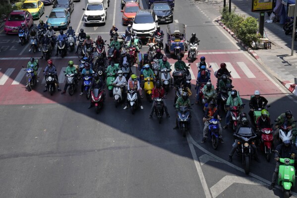 Motorcyclists stop in the shade of a skytrain line on a hot day in Bangkok, Thailand, Friday, May 3, 2024. (AP Photo/Sakchai Lalit)