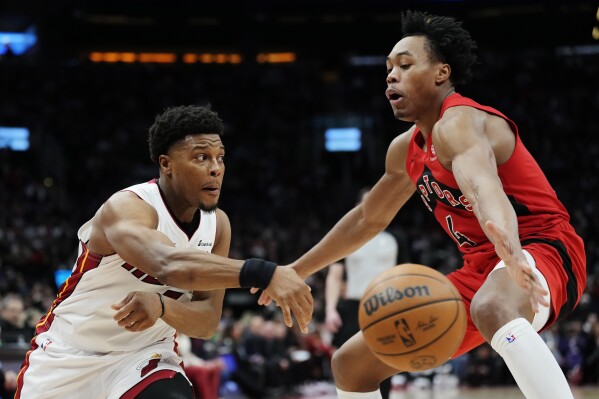 Miami Heat guard Kyle Lowry (7) passes the ball around Toronto Raptors forward Scottie Barnes (4) during the second half of an NBA basketball game Wednesday, Jan. 17, 2024, in Toronto. (Frank Gunn/The Canadian Press via AP)