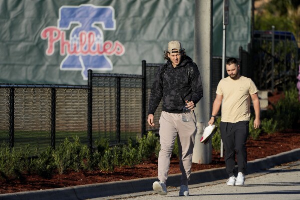 Philadelphia Phillies first baseman Alec Bohm, left, arrives for a baseball spring training workout Wednesday, Feb. 14, 2024, in Clearwater, Fla. (AP Photo/Charlie Neibergall)