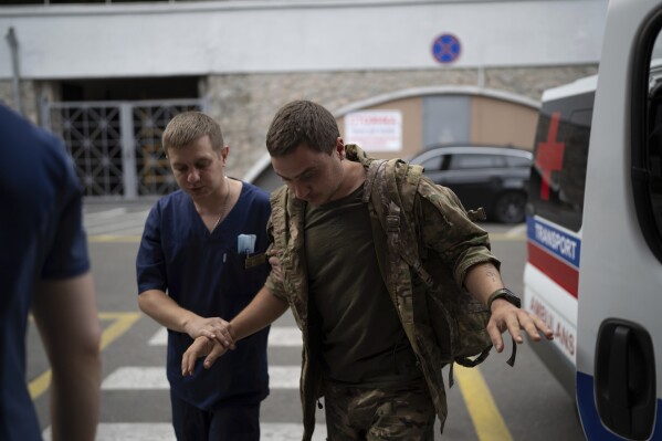 A medical worker helps a shell-shocked Ukrainian serviceman enter Mechnikov hospital in Dnipro, Ukraine, Friday, July 14, 2023. A surge of wounded soldiers has coincided with the major counteroffensive Ukraine launched last month to try to recapture its land from Russian forces. Surgeons at Mechnikov Hospital, one of the country's biggest, are busier now than perhaps at any other time since Russia began its invasion 17 months ago. (AP Photo/Evgeniy Maloletka)