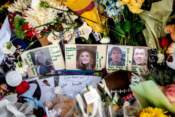 Photographs of four students — Hana St. Juliana, 14; Madisyn Baldwin, 17; Tate Myre, 16; and Justin Shilling, 17 — sit among bouquets of flowers, teddy bears and other personal items left at the memorial site for victims of the school shooting, outside Oxford High School, Dec. 7, 2021, in Oxford, Mich. (Jake May/The Flint Journal via AP, File)