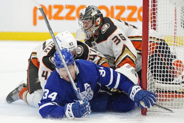 Toronto Maple Leafs' Auston Matthews (34) and Anaheim Ducks' Hampus Lindholm (47) crash into Ducks goaltender John Gibson (36) during the second period of an NHL hockey game in Toronto on Wednesday, Jan 26, 2022. (Frank Gunn/The Canadian Press via AP)