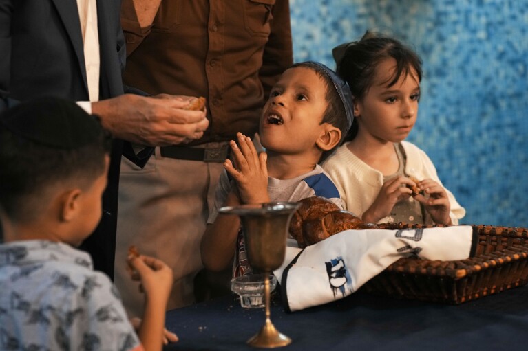 Jewish children eat pieces of challah bread after the prayer was recited during a Shabbat service at the Beth Shalom synagogue, in Havana, Cuba, Friday, Feb. 16, 2024. Jews are believed to have arrived to Cuba with Christopher Columbus in 1492, but the Cuban community officially began in the early 20th century, said the vice president of Cuba's Hebrew Community. (AP Photo/Ramon Espinosa)