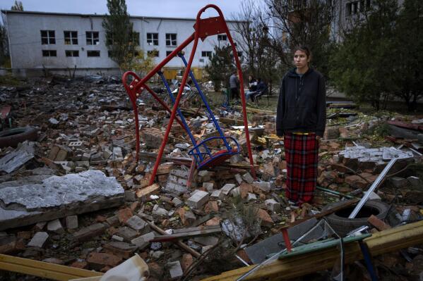 Taisiia Kovaliova, 15, stands amongst the rubble of a playground in front of her house hit by a Russian missile in Mykolaiv, Sunday, Oct. 23, 2022. "I spent all my childhood and life at this courtyard, I already feel nostalgic. I went to this swing that stood it all" Taisiia said. (AP Photo/Emilio Morenatti)