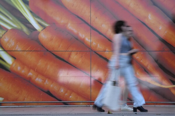 FILE - Shoppers walk past a large poster outside a supermarket in London, on June 10, 2023. Inflation in the U.K. held steady at 4% in January as lower food prices helped offset an increase in energy costs, official figures showed Wednesday, Feb. 14, 2024. The reading was better than expected as most economists expected inflation to rise modestly to around 4.2%. The Office for National Statistics said the monthly drop in food prices of 0.4% was the first since September 2021. (APPhoto/Alastair Grant)