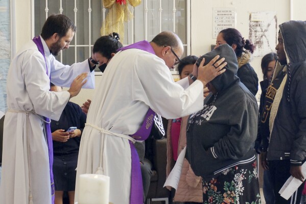 The Rev. Brian Strassburger, left, and the Rev. Flavio Bravo, right, bless migrants during Mass at the Casa del Migrant shelter in Reynosa, Mexico, on Dec. 15, 2022. (AP Photo/Giovanna Dell'Orto, File)
