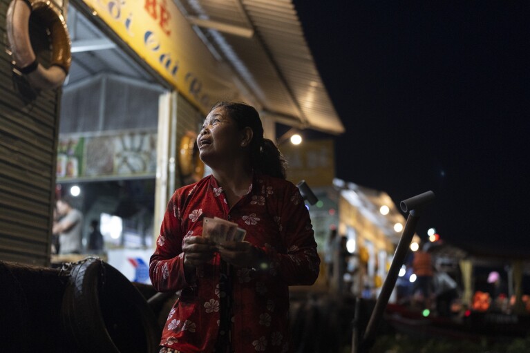 Nguyen Thi Thuy, a vendor selling steamed buns on a floating market, interacts with a customer after a sale in Can Tho, Vietnam, Wednesday, Jan. 17, 2024. (AP Photo/Jae C. Hong)