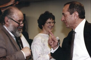 This 1991 photo provided by his daughter Leah Pike, shows retired Associated Press reporter Rayner Pike, left, during an encounter with former New York Governor Mario Cuomo. Pike, who calmly contributed his encyclopedic knowledge of news and crafty writing skills on deadline to some of New York City's biggest stories for over four decades, has died. He was 90. Surrounded by family at the end, his Dec. 26, 2023, death at home in Arlington, Mass., set off a wave of tributes from former co-workers. (AP Photo)