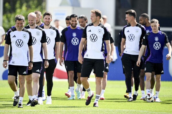 Germany's head coach Julian Nagelsmann, front center, players and staff members walk on the pitch during a training session of the German national soccer team in Herzogenaurach, Germany, Thursday, June 13, 2024. (Federico Gambarini/dpa via AP)