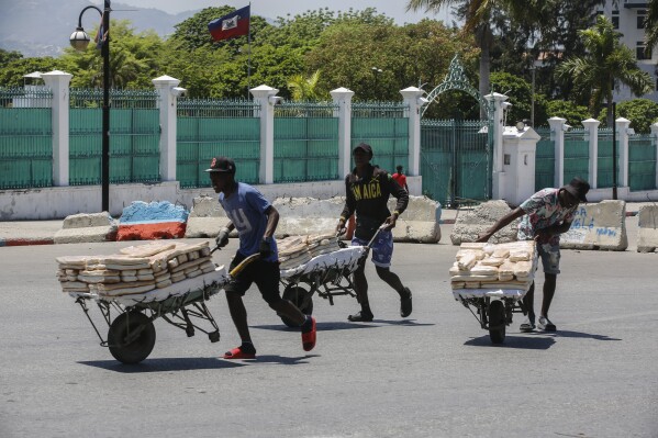Street vendors withdraw from the area where they were selling their bread, near the National Palace, in Port-au-Prince, Haiti, Tuesday, April 2, 2024. (AP Photo/Odelyn Joseph)