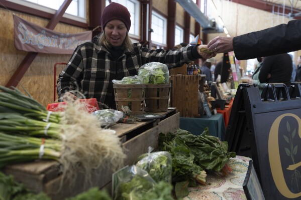 Courtney Klee, an employee of Growing Family Farms, handles a purchase at the Brighton Farmers Market on Sunday, March 23, 2025, in Brighton, N.Y. (Caitlyn Daproza via AP)