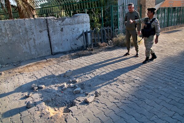 Security forces inspect the scene of the rocket attack at the gate of al-Zawra public park in Baghdad, Iraq, Wednesday, Nov. 18, 2020. Rockets struck Iraq's capital on Tuesday with four landing inside the heavily fortified Green Zone, Iraq's military said, killing a child and wounding at least five people, signaling an end to an informal truce announced by Iran-backed militias in October. (AP Photo/Khalid Mohammed)
