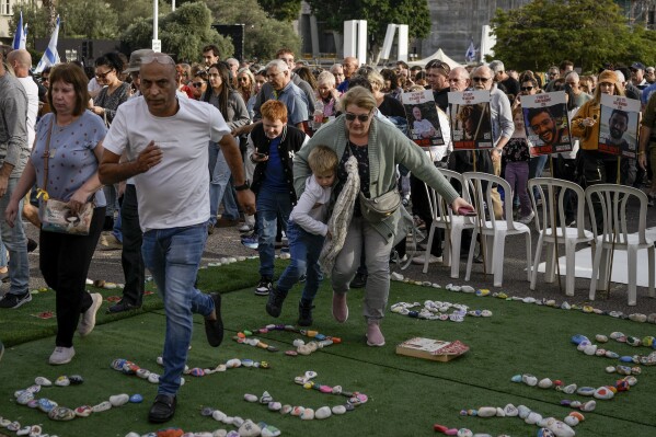 Israelis run for shelter as sirens sound warning of incoming rockets from the Gaza Strip in Tel Aviv, Israel, on Friday, Dec. 8, 2023.  (AP Photo/Leo Correa)