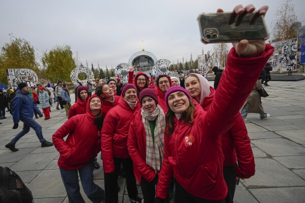 Volunteers make a selfie prior to perform during opening of the International exhibition "Russia" at VDNKh (The Exhibition of Achievements of National Economy) in Moscow, Russia, Saturday, Nov. 4, 2023. The vast show was put together under a decree from President Vladimir Putin and is seen as encouraging patriotism in the runup to the presidential election in March. (AP Photo/Alexander Zemlianichenko)