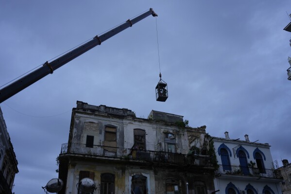 Una grúa levanta a los bomberos en una jaula hacia un edificio en busca de sobrevivientes después de que colapsara parcialmente en La Habana, Cuba, el miércoles 4 de octubre de 2023. (AP Foto/Ramón Espinosa)