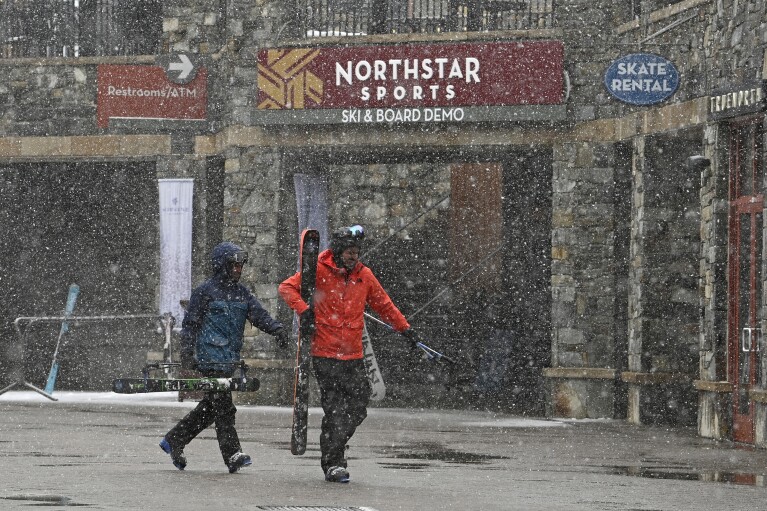Skiers rush through the Village at Northstar California Resort as snow falls in Truckee, Calif., Thursday, Feb. 29, 2024.  (AP Photo/Andy Barron)