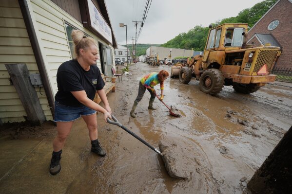 From left, Ashley Rishel from the Allegany County 911 and Lesley Moran help clean up Main Street after flooding on Wednesday, May 14, 2025 in Westernport, Md. (AP Photo/Gene J. Puskar)